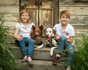two young kids and their two dogs pose for photograph sitting on rustic tin shed in brisbane photography studio