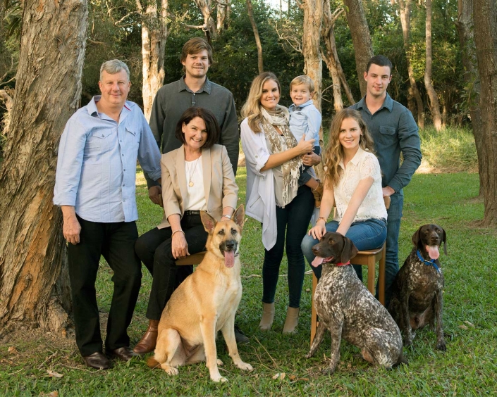 large multi generation family portrait with three dogs in front of australian native eucalyptus trees