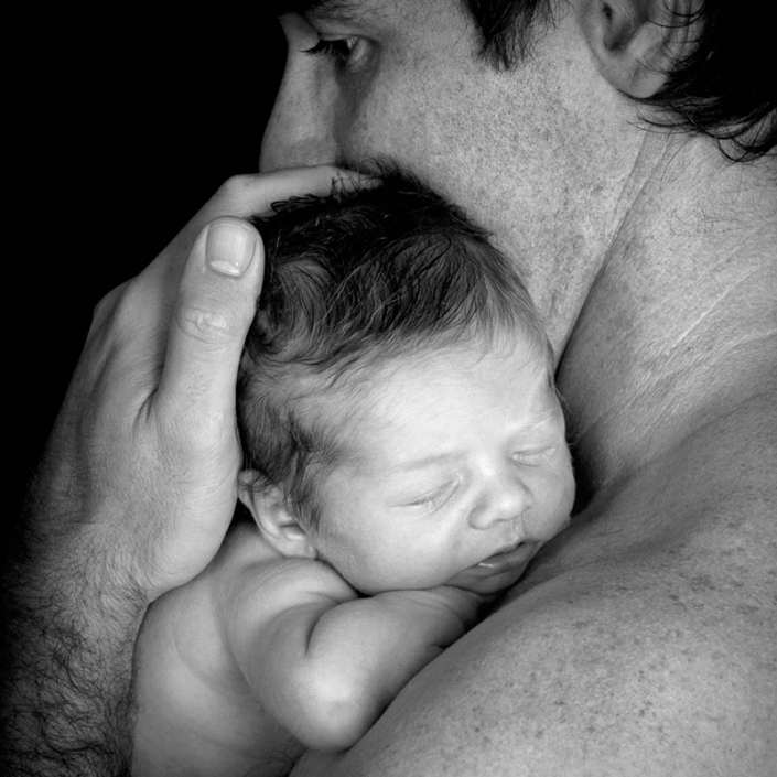 newborn father and son black and white portrait up close