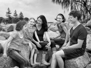 Mum and Dad on rocky beach with three kids laughing black and white image