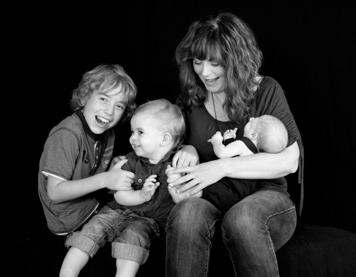 Mother and her three children wearing casual clothing for photography session in studio