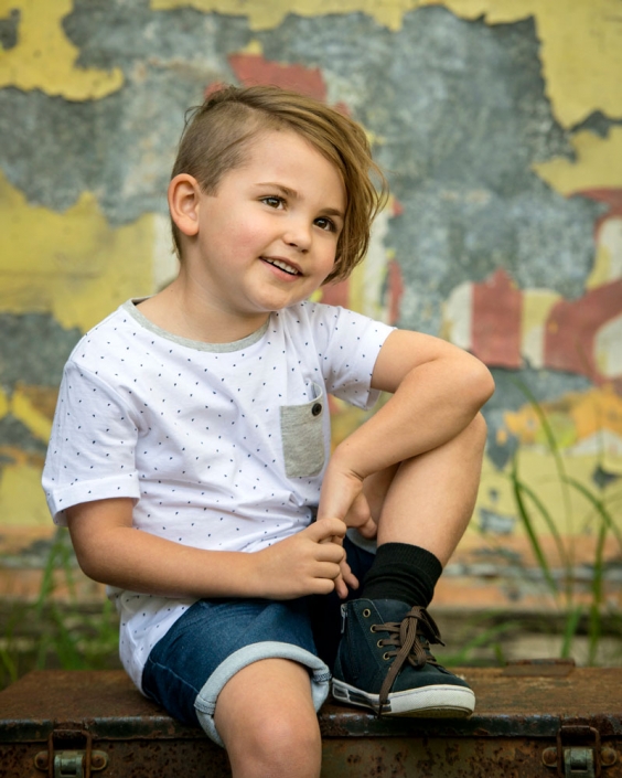 cool young boy sitting casual in front of vintage sign for children's portfolio photograph