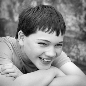 candid young teenage boy smiling naturally with arms folded in black and white