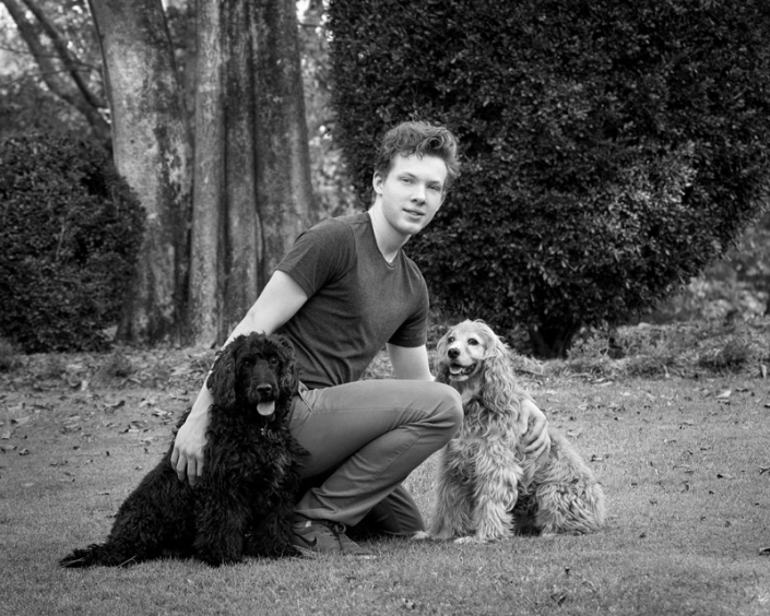 young man and two medium sized dog in new farm park