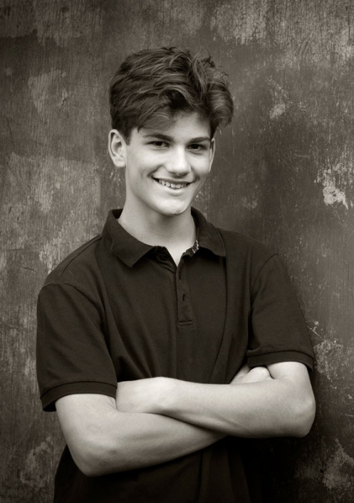 black and white image of young man wearing dark polo colour shirt with arms folded