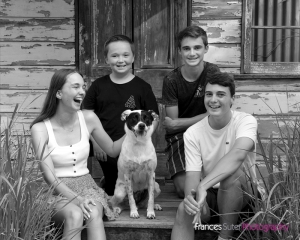 family of four teenage children sitting with their rescue dog Luna
