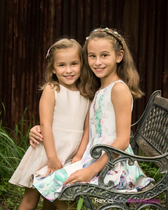 beautiful sisters sitting on garden chair for children's photography session
