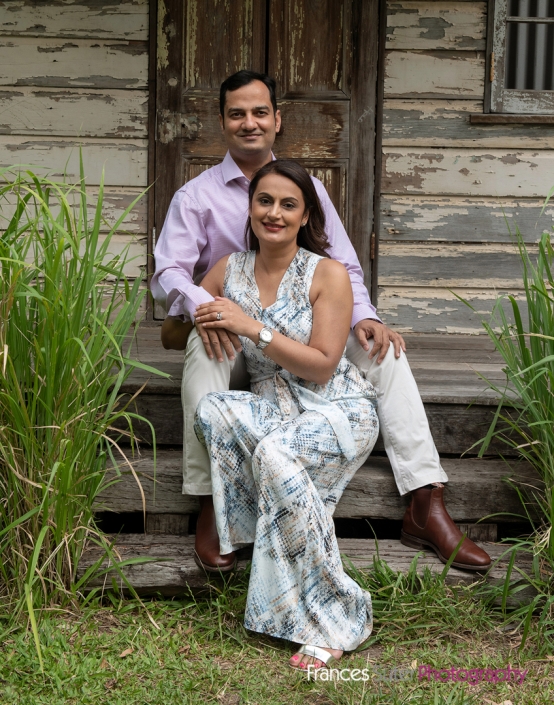 husband and wife sitting relaxed in front of farmhouse shed backdrop for photograph