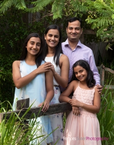 family photography in garden of dad with his three daughters wearing pastel coloured clothing