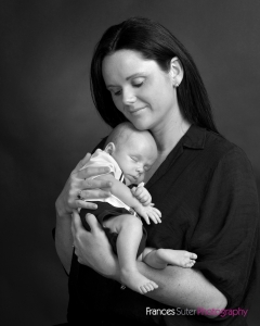 Mother holds her newborn son close to her chest photograph in black and white