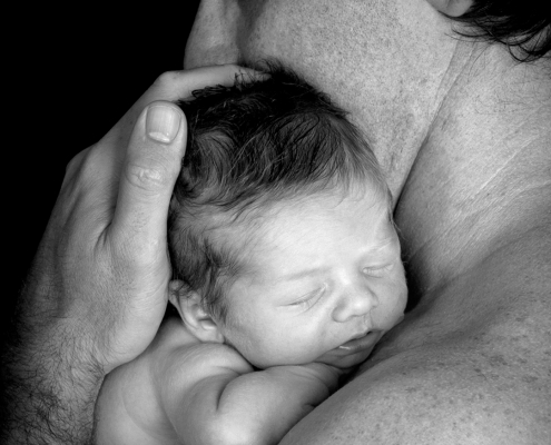 black and white image of father holding newborn baby