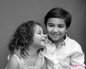 black and white image of young brother and sister posing happily in outdoor photography studio Brisbane