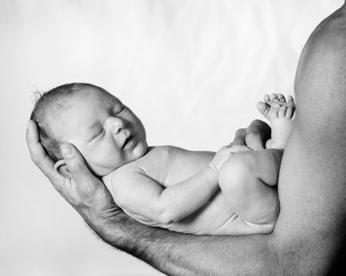 newborn baby sleeping in Father's arms